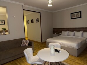 Ein modernes Schlafzimmer mit Bett, einer Couch, einem Couchtisch und einem Spiegel.
