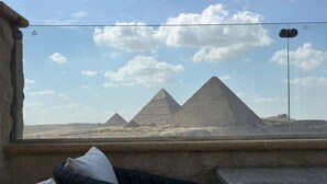 Vista de las pirámides desde una ventana, con una silla de mimbre y un cojín blanco.