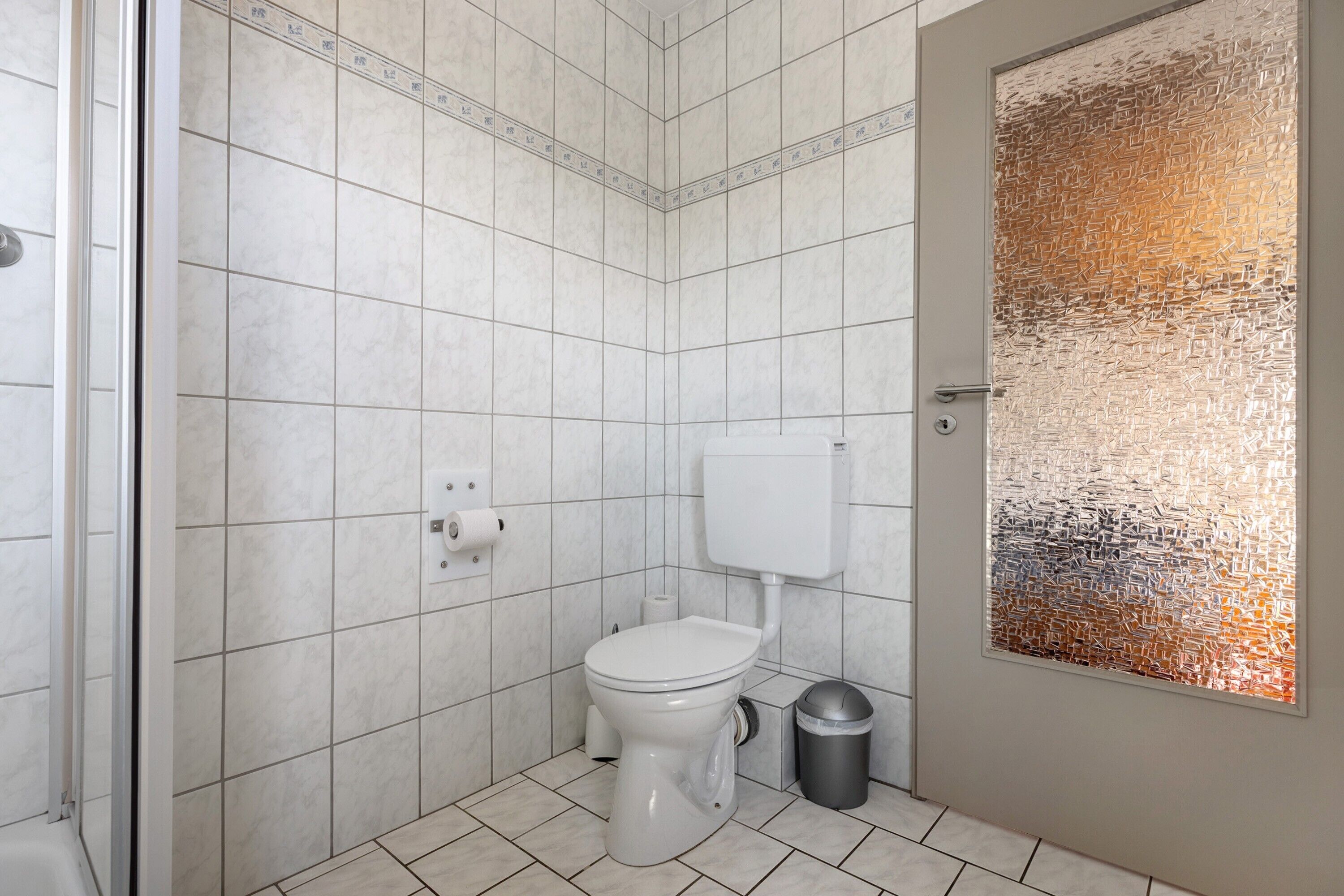 Un bagno con il water, un cestino e una zona doccia.