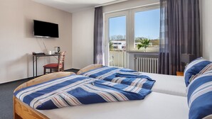 A hotel room with a bed, a desk with a chair, a television, and a window with curtains. - Room "Room 2" with Balcony (Extertal)
