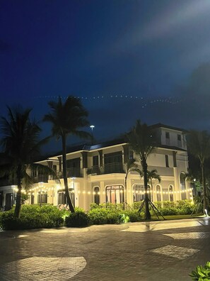 Un hôtel à plusieurs étages doté d’une cour intérieure, de palmiers et de guirlandes lumineuses.