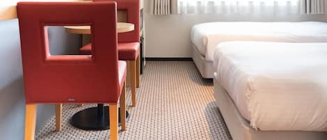 Habitación de hotel con una cama, un escritorio con silla, un televisor y una ventana con cortinas.