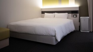 Een hotelkamer met een bed, nachtkastje, lamp, klok en verwarming.