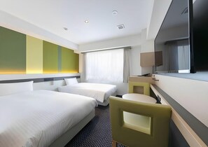 Ein Hotelzimmer mit zwei Betten, einem Schreibtisch, einem Stuhl, einem Fernseher und einem Fenster mit Vorhängen.