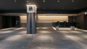Een ruime lobby met een centrale pilaar, een receptiebalie en een modern ontwerp.