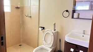 A bathroom with a toilet, sink, and shower.