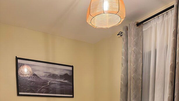 A neatly made bed with white and black bedding, a framed picture on the wall, and a bedside lamp.