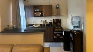 A compact kitchen with a microwave, stove, and water dispenser.