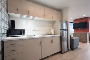 Een koelkast, een magnetron, een kookplaat, kookgerei, borden en bestek