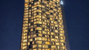 Un hotel moderno y alto, con fachada uniforme y numerosas ventanas iluminadas.