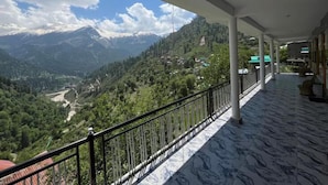A balcony with a view of a mountainous landscape, a clear sky, and a paved floor. - Yellowjackets Hotel Tosh (Tosh)
