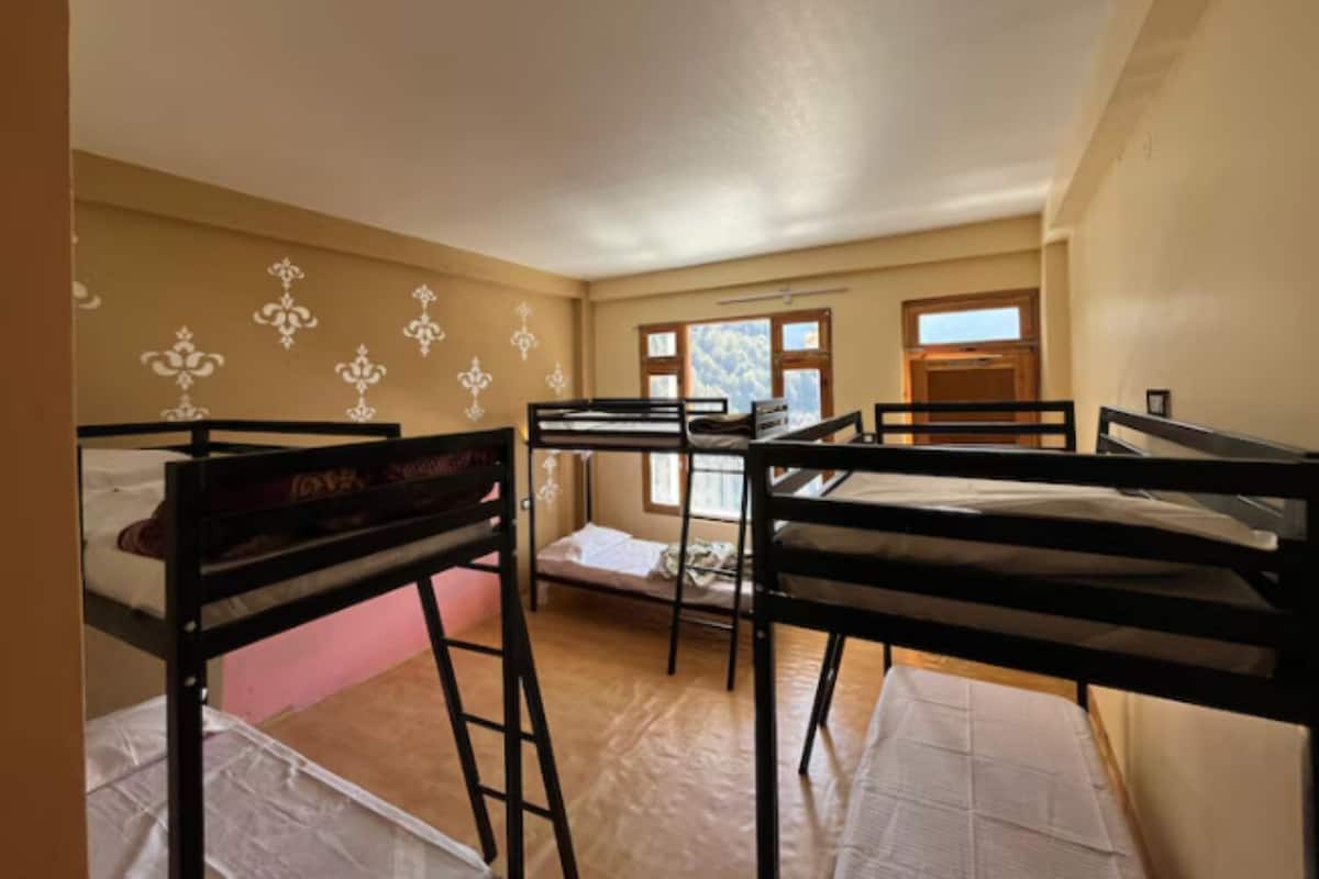 Un dormitorio con literas, una mesita pequeña y una ventana con vistas a árboles.
