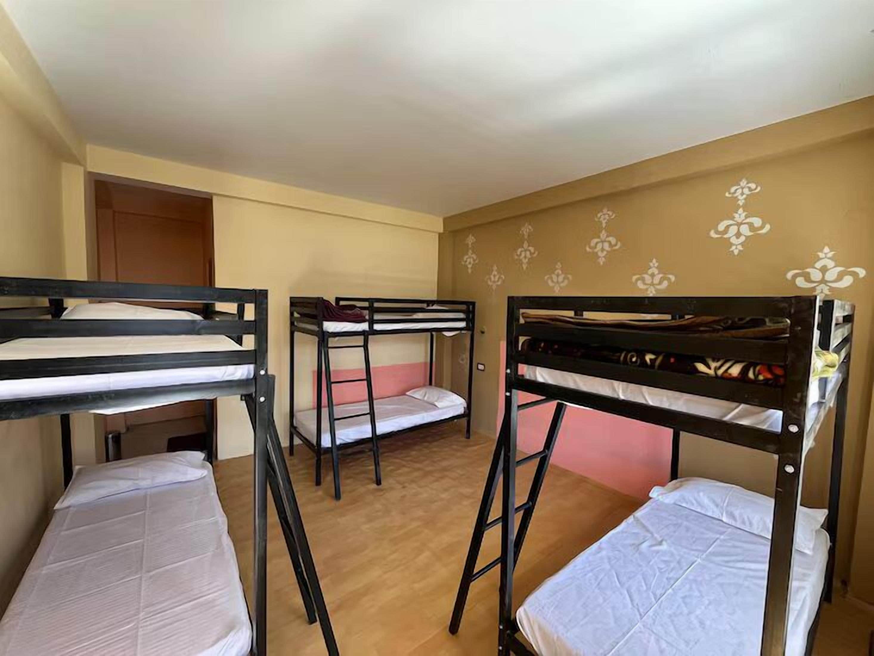 Una habitación con literas, piso de madera y papel tapiz estampado.
