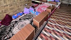 A room with a wooden ceiling, hanging lights, a patterned carpet, and a long sofa with cushions. - Yellowjackets Hotel Tosh (Tosh)