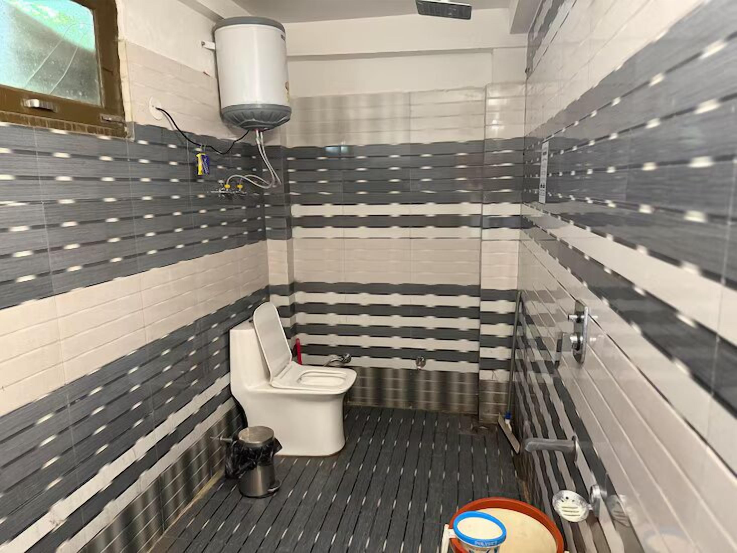 A bathroom with a toilet, a trash bin, a bidet, and a shower area.