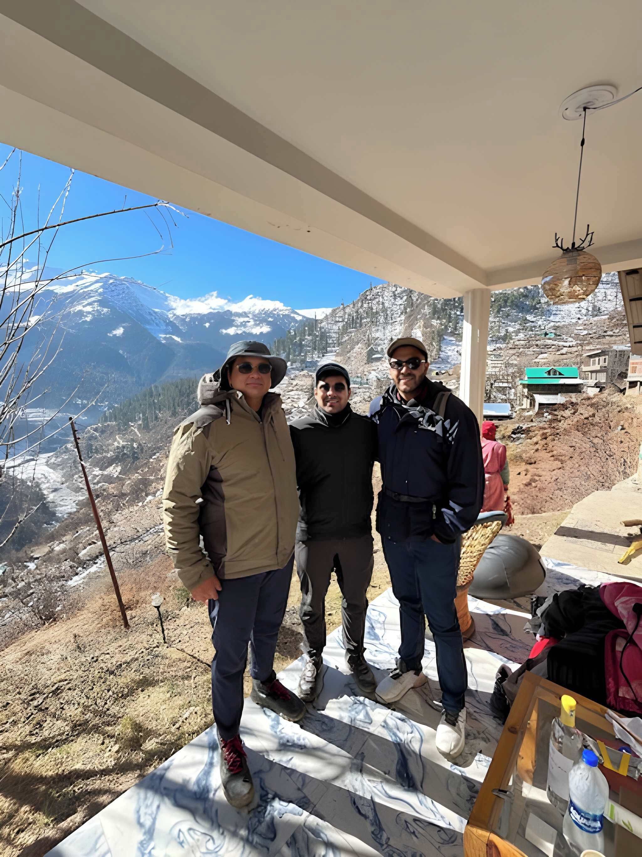 Three people standing indoors with a mountain view.