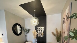 Un espace de salle à manger moderne avec une table noire, des chaises blanches, un miroir décoratif et un design de plafond original.