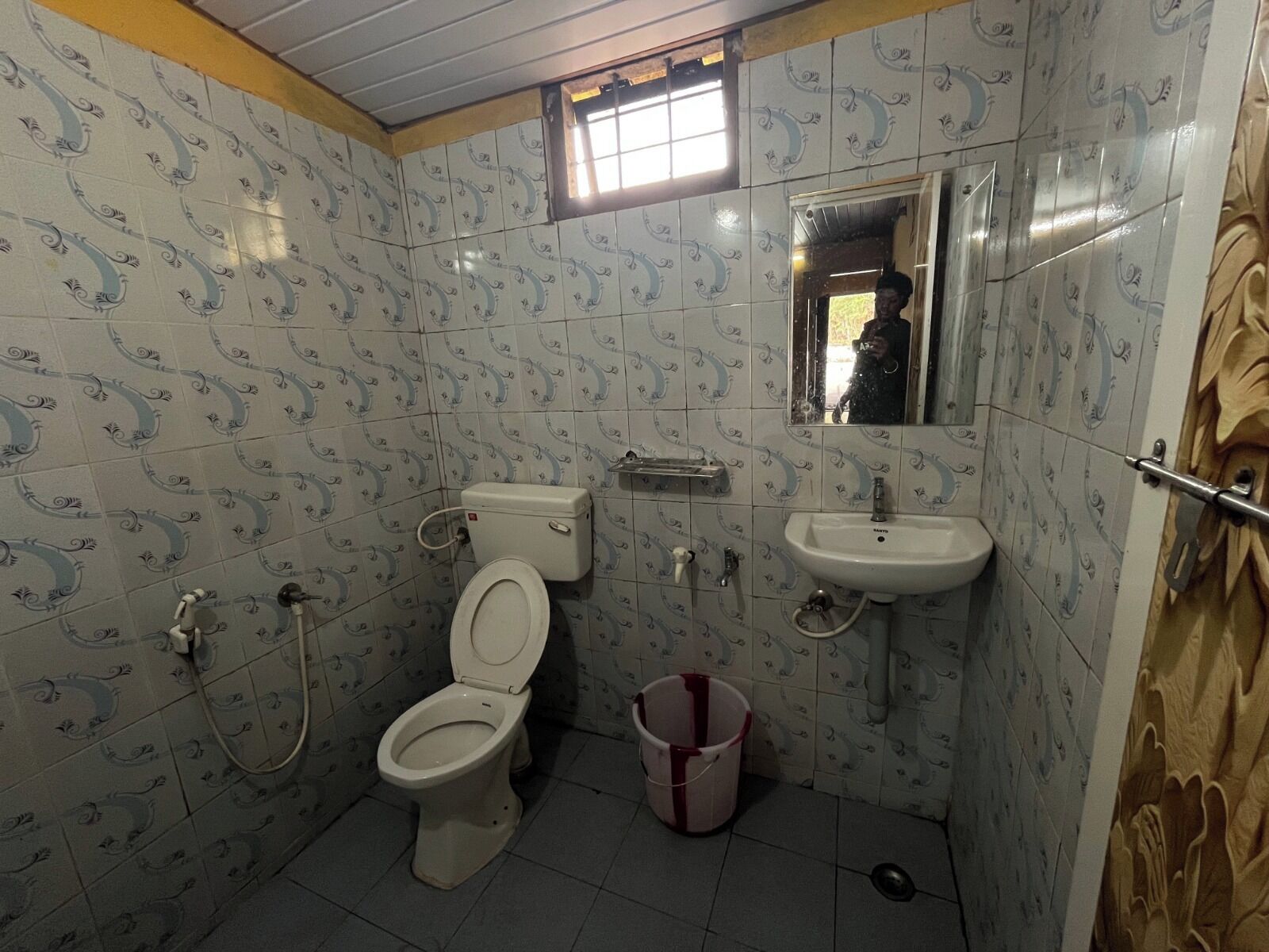 A small bathroom with a toilet, sink, and a window above the sink.