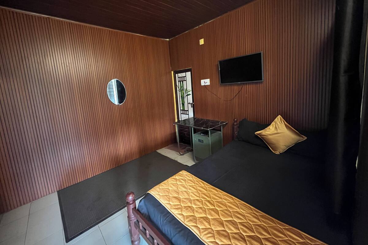 Une chambre avec un lit, un bureau et un téléviseur fixé au mur.