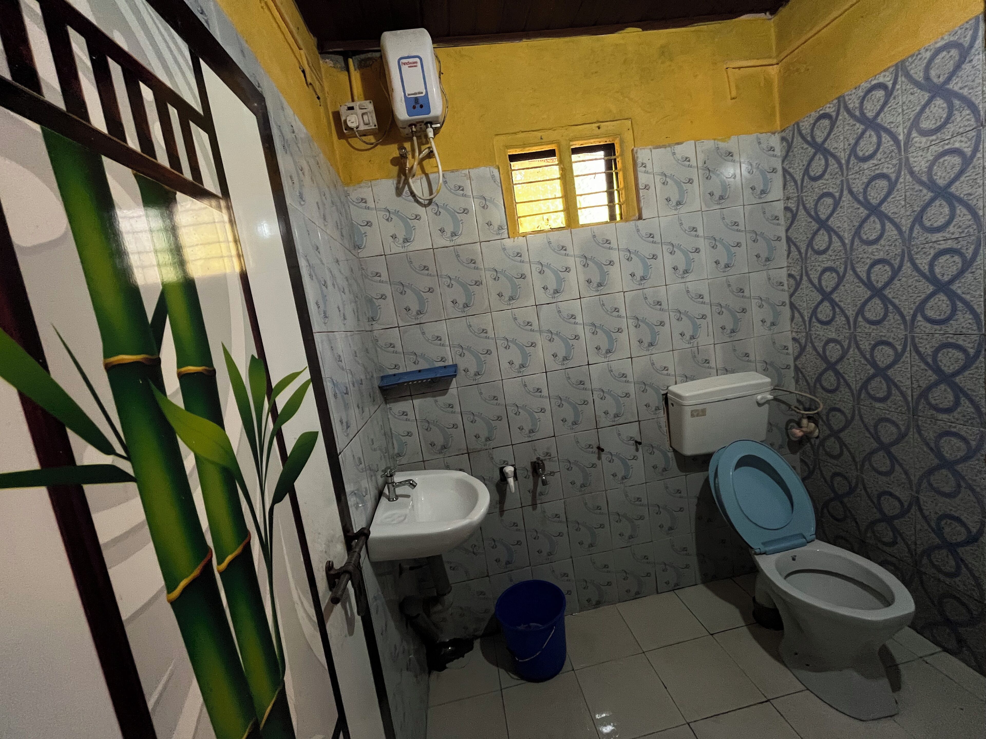 Une petite salle de bain comprenant des toilettes, un lavabo et un chauffe-eau fixé au mur.