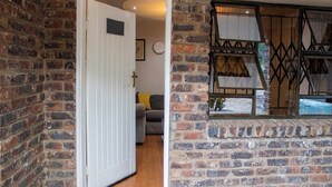 A room with a brick wall, a white door, a sofa, and a window with a metal frame. - Chishongo residence, your peaceful Darwendale getaway (Zvimba)