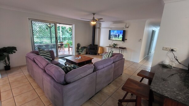 A living room with a sofa, a coffee table, a TV, a fireplace, and a balcony with a view. - Relaxing country home half way between Gold Coast and Brisbane (Wolffdene)