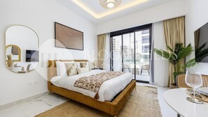A modern bedroom with a bed, a dining table, and a large window. - Bloomfields Elegant Stu in Azizi (Dubai)