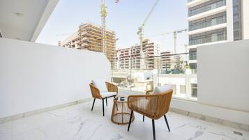 Un balcone con mobili in vimini e pavimento in marmo, vista su un cantiere con gru.