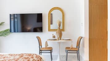 Una camera d'albergo con un letto, una TV a parete, un tavolo rotondo con sedie e un armadio.