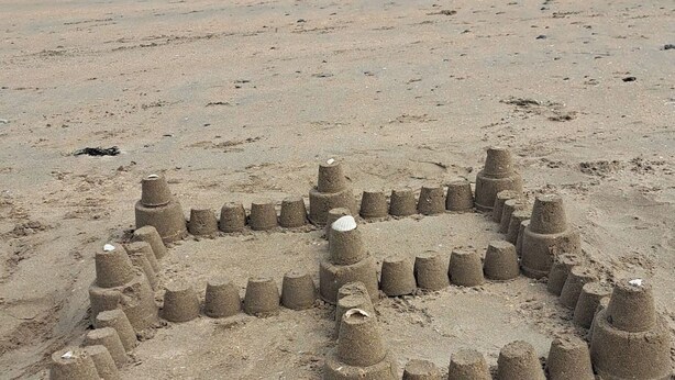 Une plage de sable ornée d  ’une grande sculpture de sable représentant un visage.