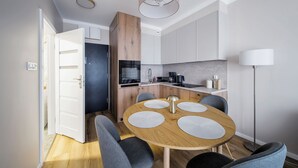A modern kitchen with a round wooden table, grey chairs, and a pendant light.