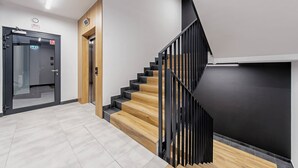 A modern interior with a staircase, a door with an emergency exit sign, and a light fixture on the ceiling.