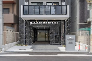 The entrance of Apartment Hotel 11 with a modern design, featuring a prominent entrance and a signboard. - Apartment Hotel 11 Dotonbori 8 (Osaka)