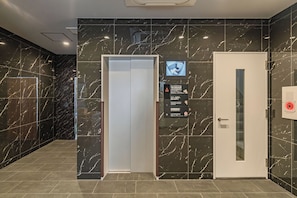 A modern elevator with a digital display, a non-smoking sign, and a door with a glass panel. - Apartment Hotel 11 Dotonbori 8 (Osaka)