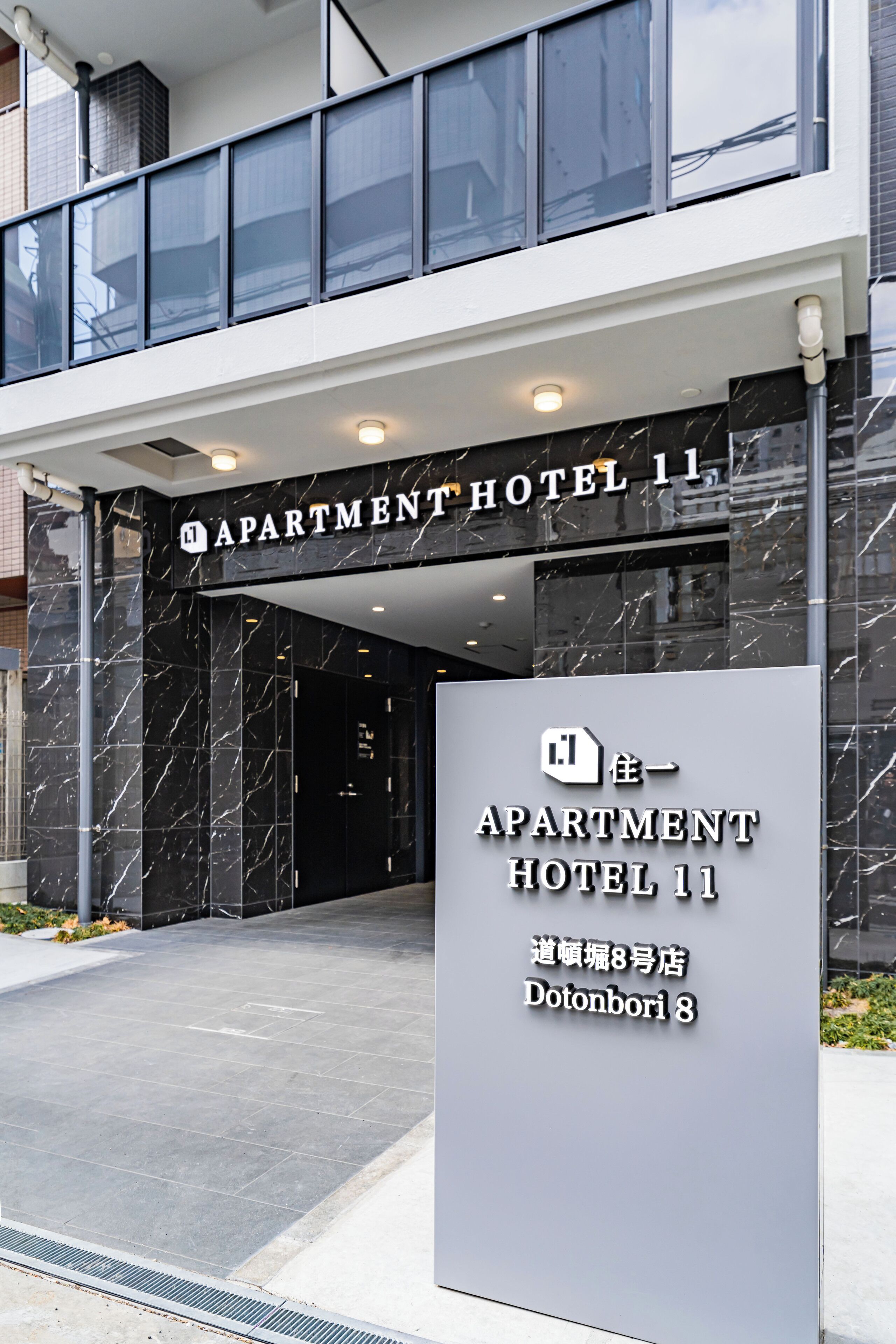 The entrance to Apartment Hotel 11 with a sign indicating its location at Dotonbori 8.