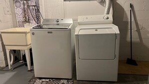 A laundry area with a Maytag washer and dryer, a small table, and a patterned rug. - Prime Location Studio with Separate amenities (London)