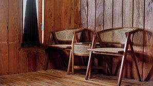 A wooden interior with two wicker chairs and a wooden floor. - Emerald Cabin Dieng (Kejajar)