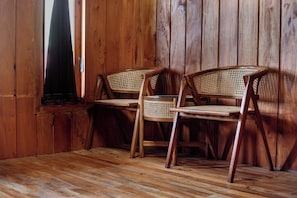 A wooden interior with two wicker chairs and a wooden floor. - Emerald Cabin Dieng (Kejajar)