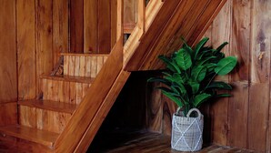 A wooden staircase with a woven basket containing green plants. - Emerald Cabin Dieng (Kejajar)