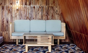 A wooden interior with a light blue sofa and a wooden table. - Emerald Cabin Dieng (Kejajar)