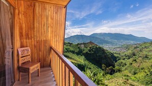 A wooden balcony with a wooden chair, overlooking a mountainous landscape. - Emerald Cabin Dieng (Kejajar)