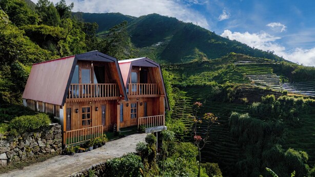 A wooden house with a balcony, set in a lush valley with terraced fields. - Emerald Cabin Dieng (Kejajar)