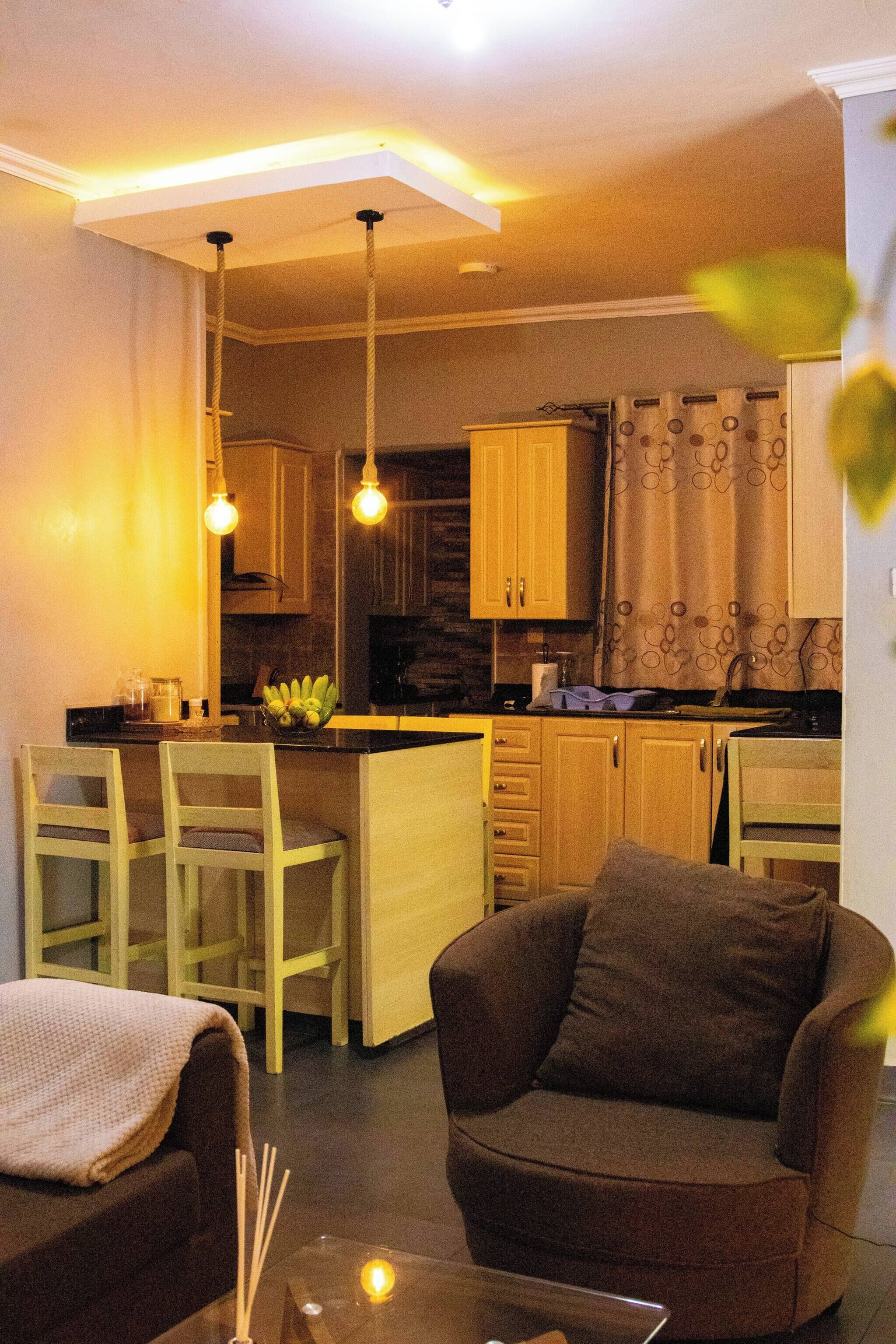 A compact living space with a kitchen area, a dining table with chairs, and a sofa with a cushion.