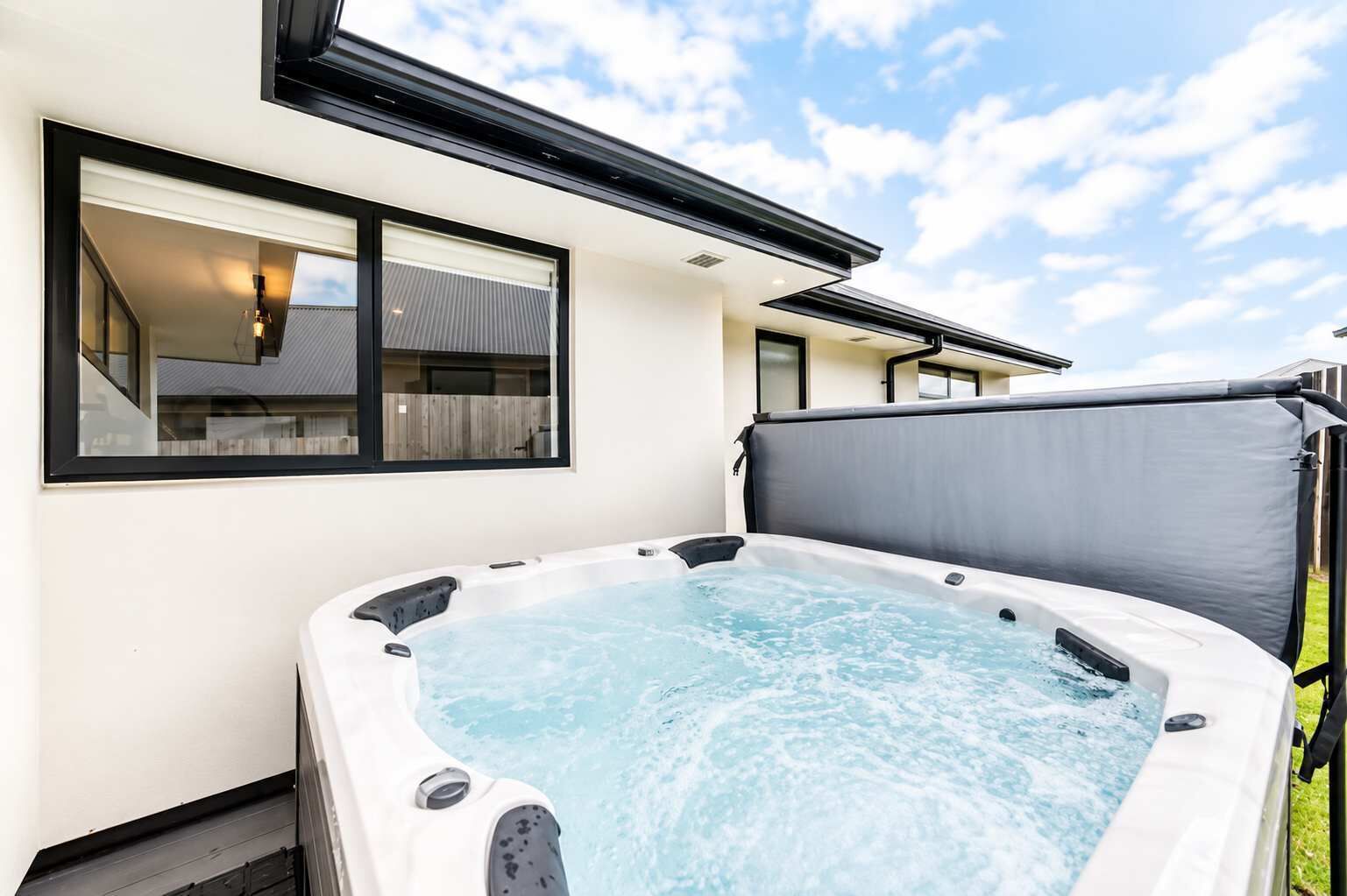 A hot tub in a backyard with a house in the background.