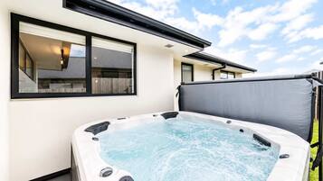 A hot tub in a backyard with a house in the background.