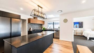 A modern kitchen with a central island, built-in appliances, and a contemporary light fixture.