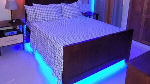 Une chambre à coucher comprenant un lit, des tables de chevet, un ventilateur de plafond et un éclairage décoratif à LED.