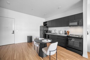 Una cocina moderna con armarios oscuros, un microondas, una estufa y un comedor con mesa y sillas.