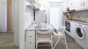Ett kompakt kök med en matplats, inklusive ett bord, stolar, en tvättmaskin och en liten ugn.