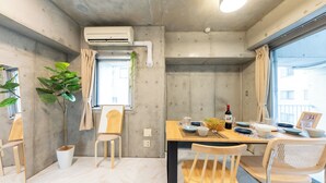 Un espacio habitable pequeño con zona de comedor, una planta en maceta y ventana con cortinas.